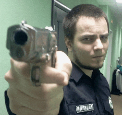 a man in a police uniform is pointing his gun at the camera