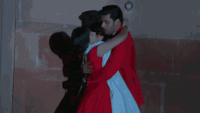 a man in a red suit holds a woman in a white dress