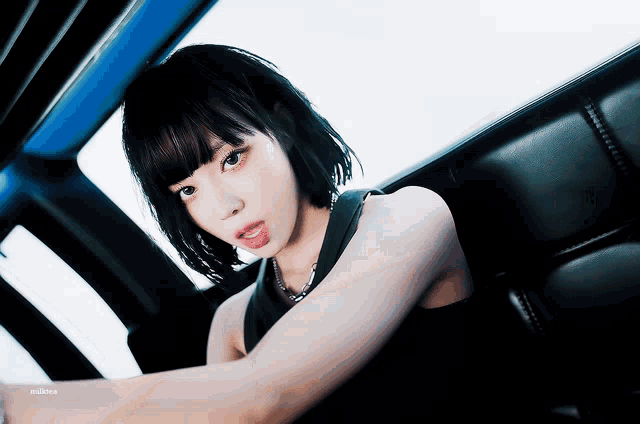 a woman with short black hair is sitting in the back seat of a car with her tongue hanging out