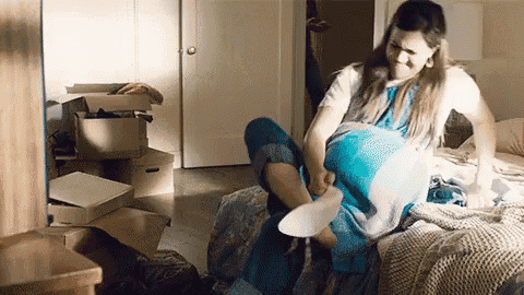 a woman is sitting on a bed putting on a pair of shoes .