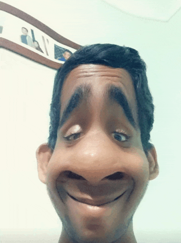 a man making a funny face in front of a framed picture