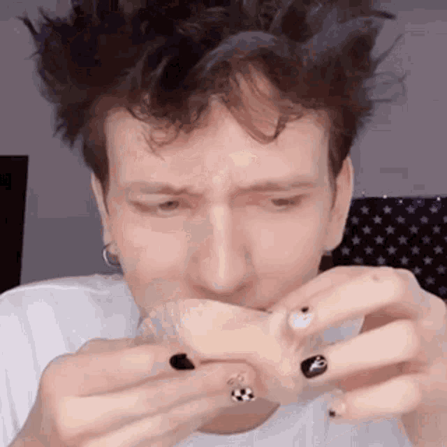 a man with black nails is holding a piece of food in his hands .