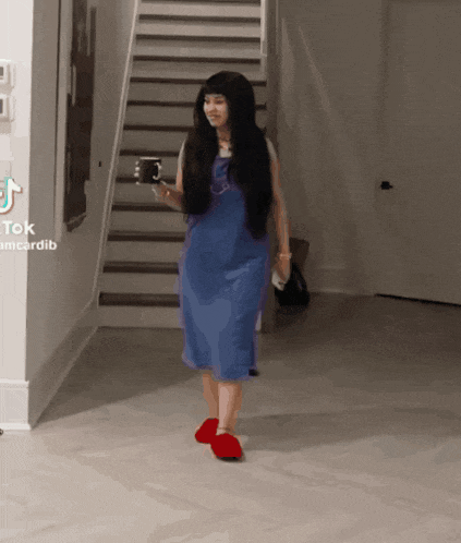 a woman wearing a blue dress and red slippers is walking down stairs