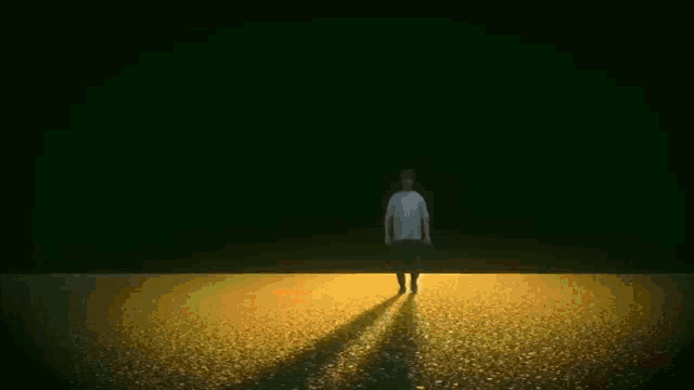 a man is walking through a field with fire coming out of it at night .