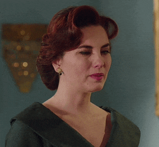 a woman with red hair is wearing a black dress and earrings