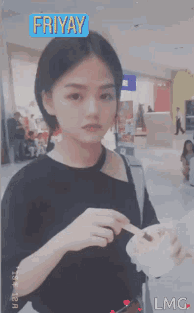 a girl in a black shirt is holding a piece of ice cream in front of a sign that says friday