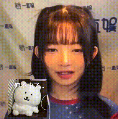 a girl with a ponytail and bangs is smiling next to a stuffed animal