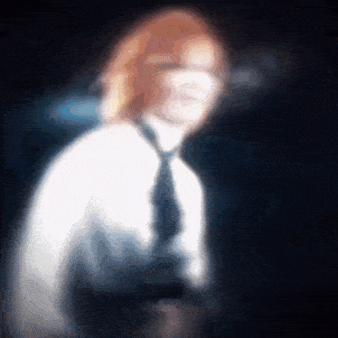 a blurry picture of a man with red hair wearing a white shirt and tie