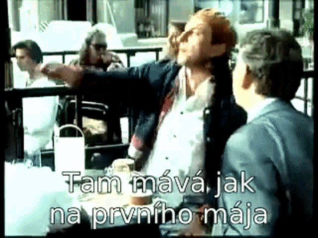 two men are sitting at a table with the words tam mava jak na prvniho maja