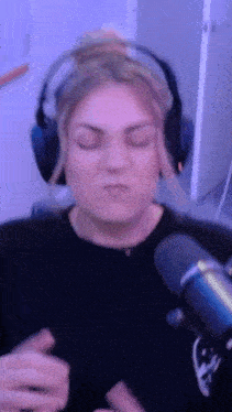 a woman wearing headphones is standing in front of a microphone .