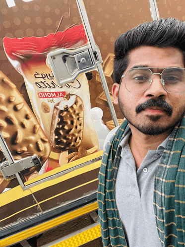 a man wearing glasses stands in front of a bag of ice cream that says " oiom ja "