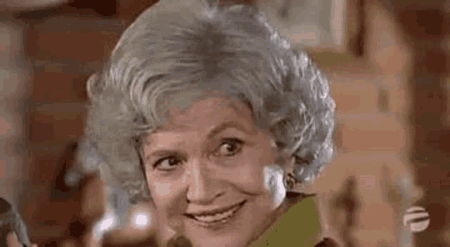 a close up of a woman with gray hair smiling .