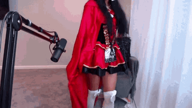 a woman in a red cape stands in front of a microphone