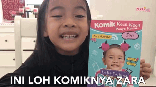 a little girl is holding a book called komik kecil kecil punya karya