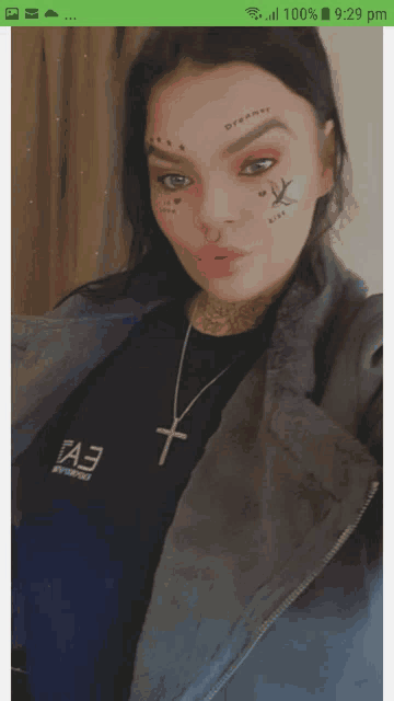 a woman with tattoos on her face is wearing a black shirt that says fa3