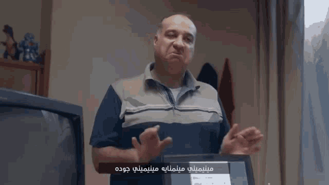 a man making a funny face while standing in front of a television