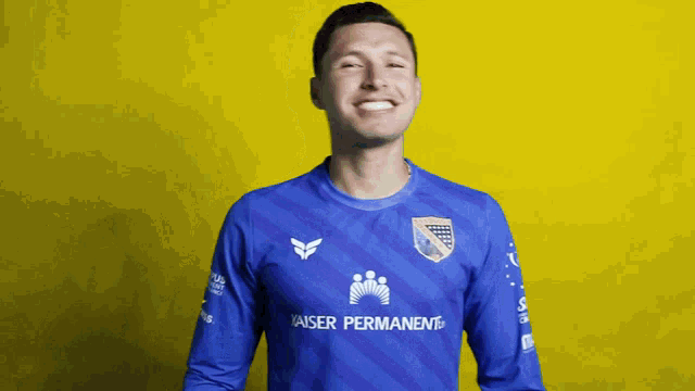 a man wearing a blue kaiser permanent shirt smiles