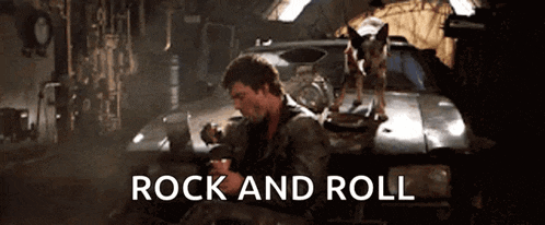 a man sitting in front of a car with a dog on top of it and the words rock and roll below him