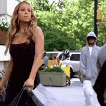a woman in a black dress is walking down a street with shopping bags
