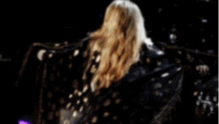 a woman with long blonde hair is standing in a dark room .
