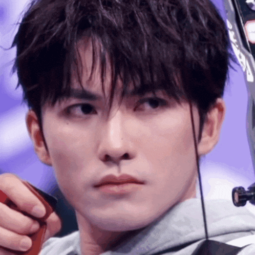 a young man is holding a bow and arrow and looking at the camera .