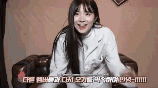 a young girl is sitting on a couch and smiling in a video .