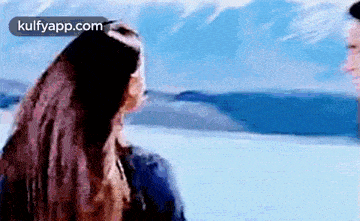 a man and a woman are standing next to each other in front of a lake .
