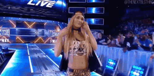 a woman is standing on a stage in front of a crowd in a wrestling ring .