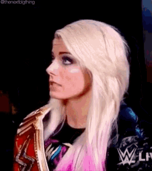 a woman with blonde hair and pink highlights is holding a wrestling championship belt .