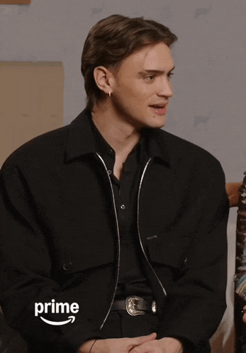 a man wearing a black shirt and a black jacket with the word prime on the bottom