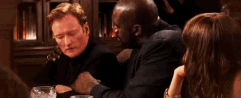a group of people are sitting at a table talking to each other .