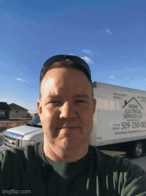 a man taking a selfie in front of a home electrical service truck