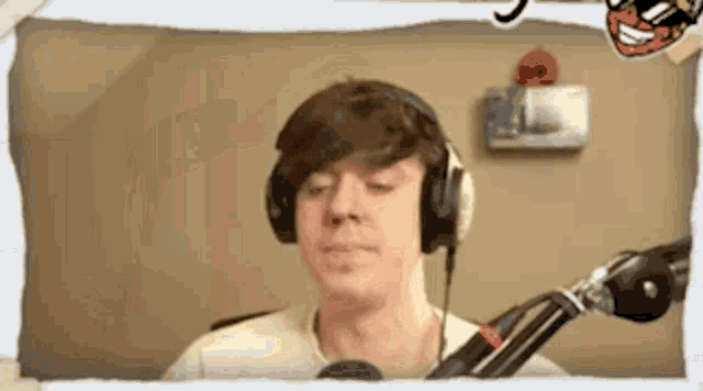 a man wearing headphones is standing in front of a microphone and making a funny face .