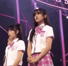 a group of girls are standing on a stage wearing school uniforms .