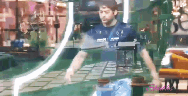 a man in a blue shirt is standing in front of a table with a lantern on it .