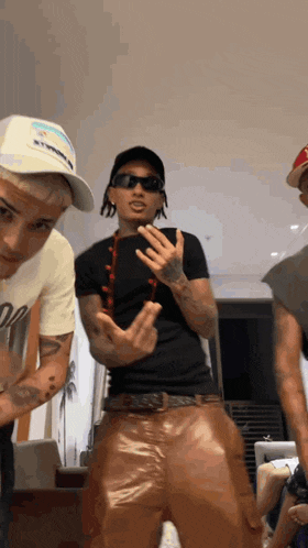 a group of men are standing in a room and one of them is wearing sunglasses