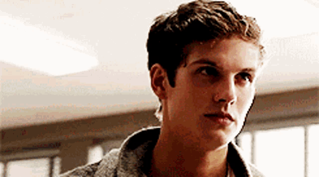 a close up of a young man 's face in a room with a window .