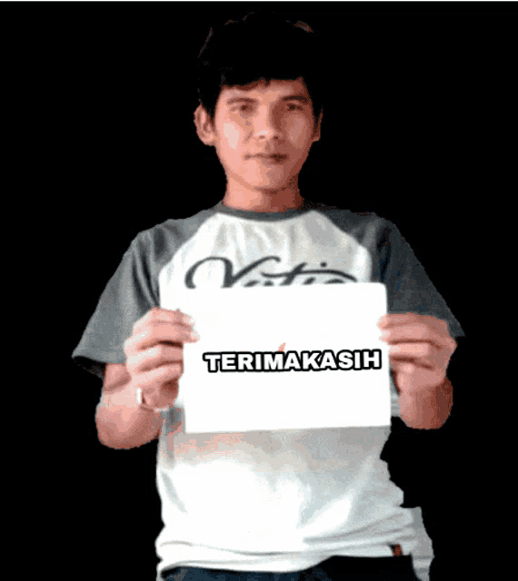 a man holding a sign that says terimakasih