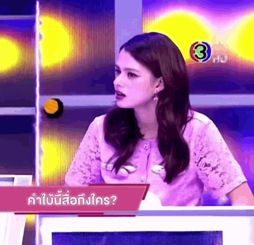 a woman in a purple shirt is sitting at a table with a sign that says 3 hd on it .