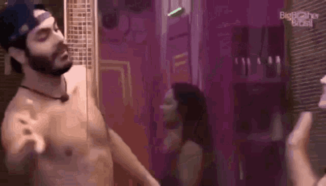 a man without a shirt is standing next to a woman .
