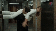 a man is carrying a woman upside down in his arms in an elevator .