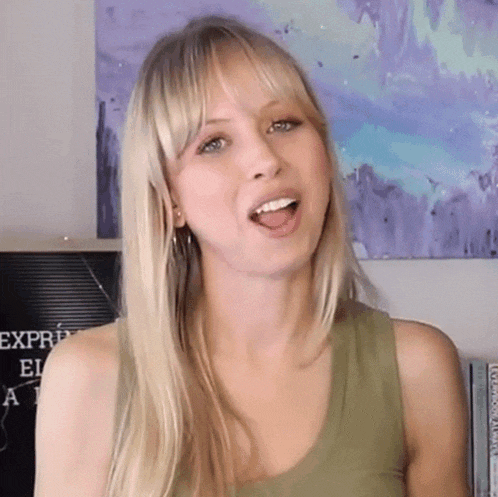 a woman in a green tank top is making a funny face with her tongue out .