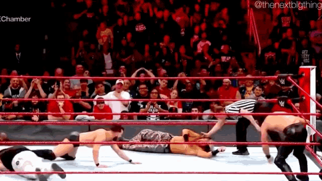 a group of men are wrestling in a wrestling ring with a referee in the background .