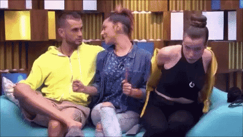 a man and two women are sitting on a blue couch talking to each other