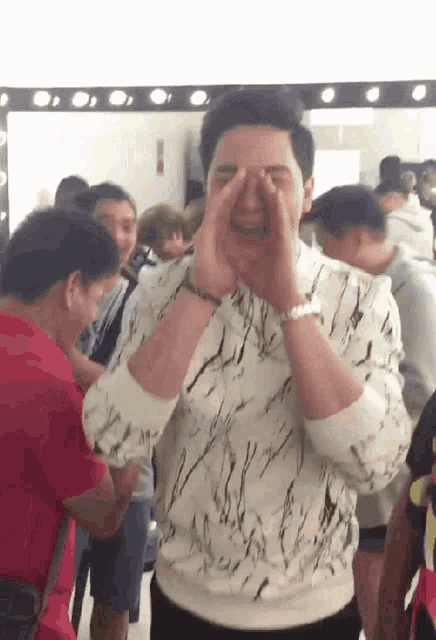 a man covering his face with his hands in front of a mirror