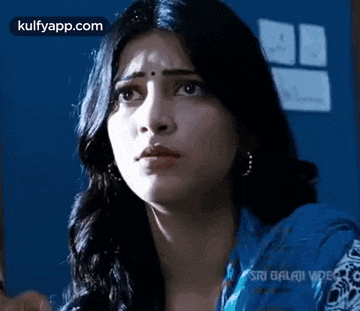 a close up of a woman 's face with a blue background and a blue shirt .