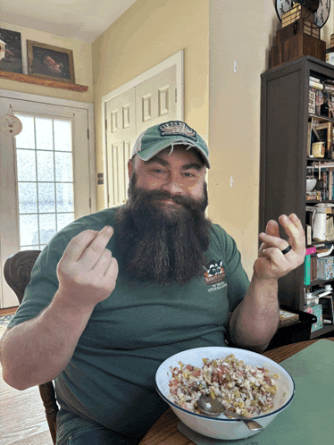 a man with a beard is sitting at a table eating cereal