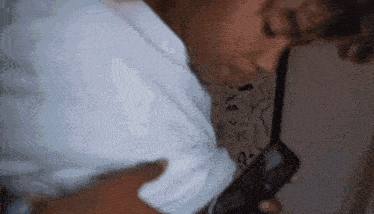 a man in a white shirt holds a cell phone in his hand