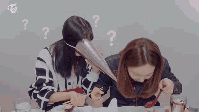 two women sitting at a table with a cone on their head and a twice logo on the bottom right