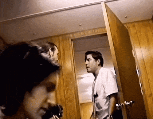 two men are standing next to each other in a room with wood paneling .